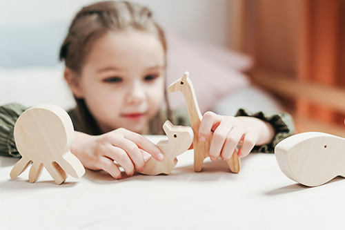 child interacting with wood animals